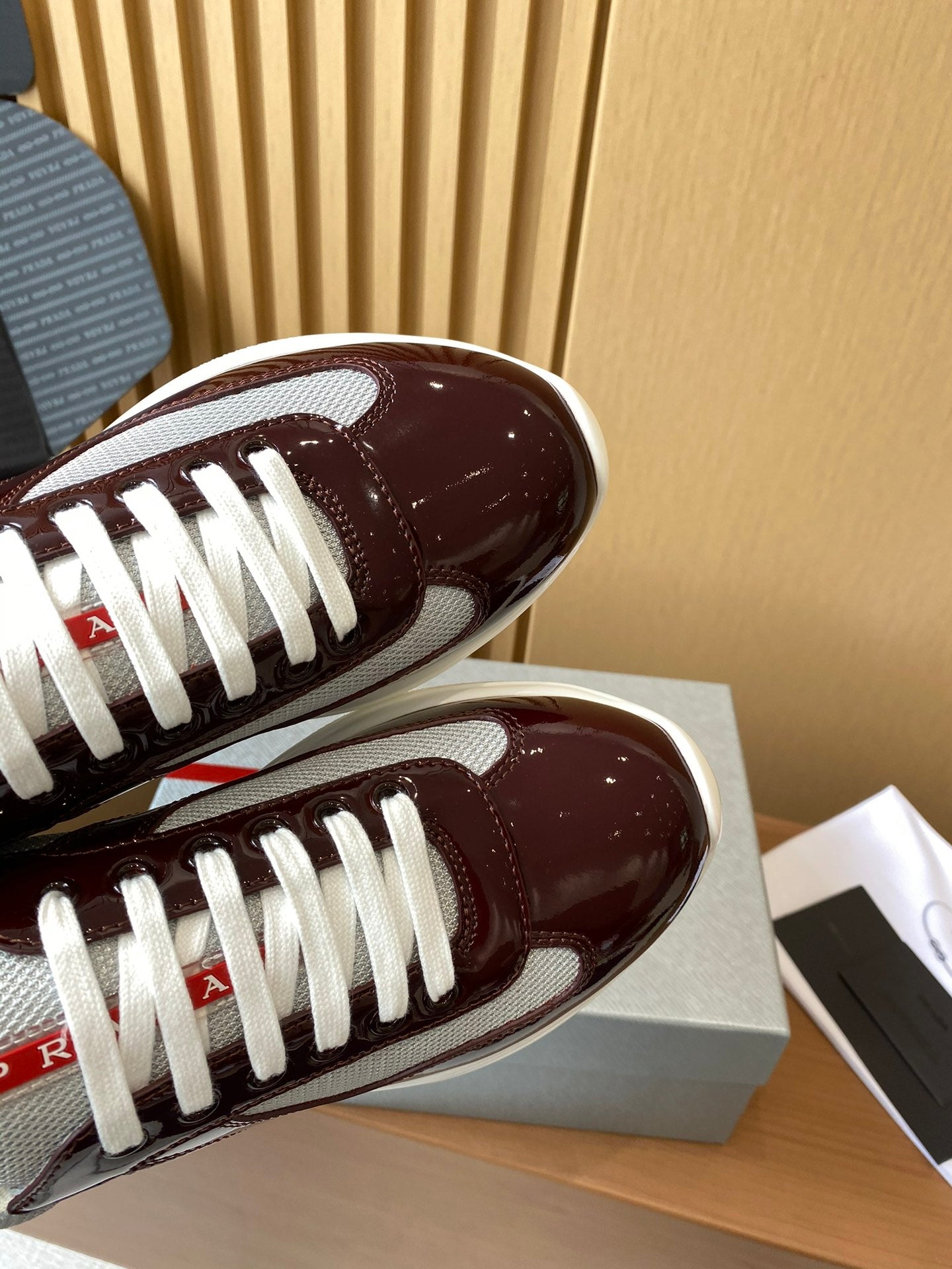 Close-up of burgundy sneaker toe with white laces and glossy patent finish