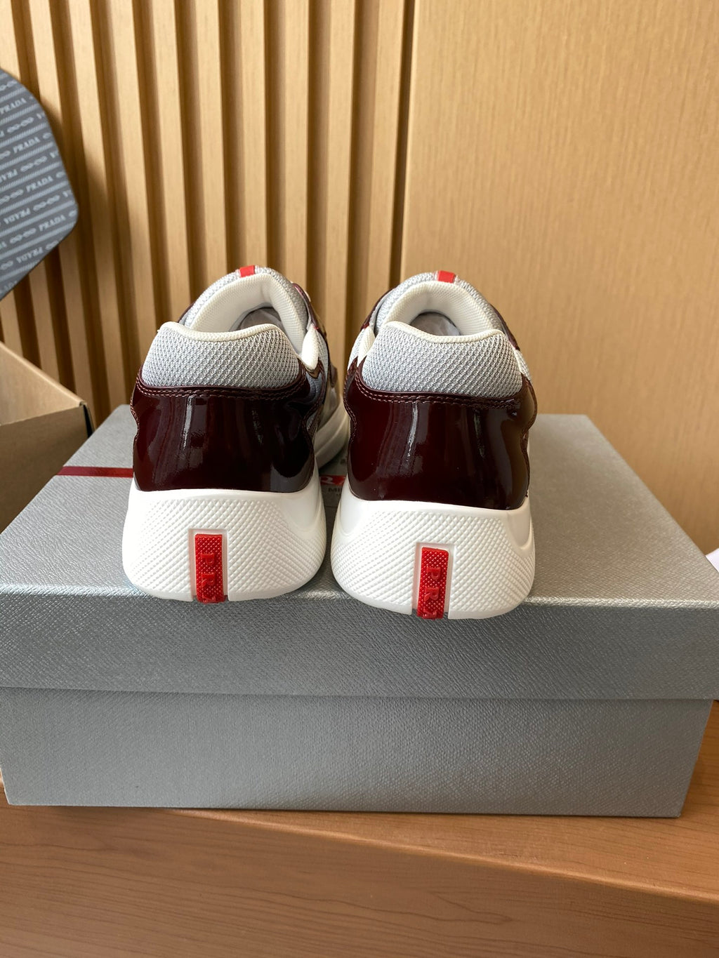 Pair of burgundy low-top sneakers with white heels and red vertical logo accents