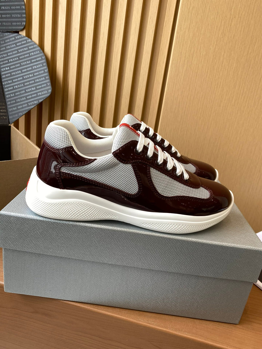 Burgundy and white low-top sneakers with white laces and side panels, red logo detail