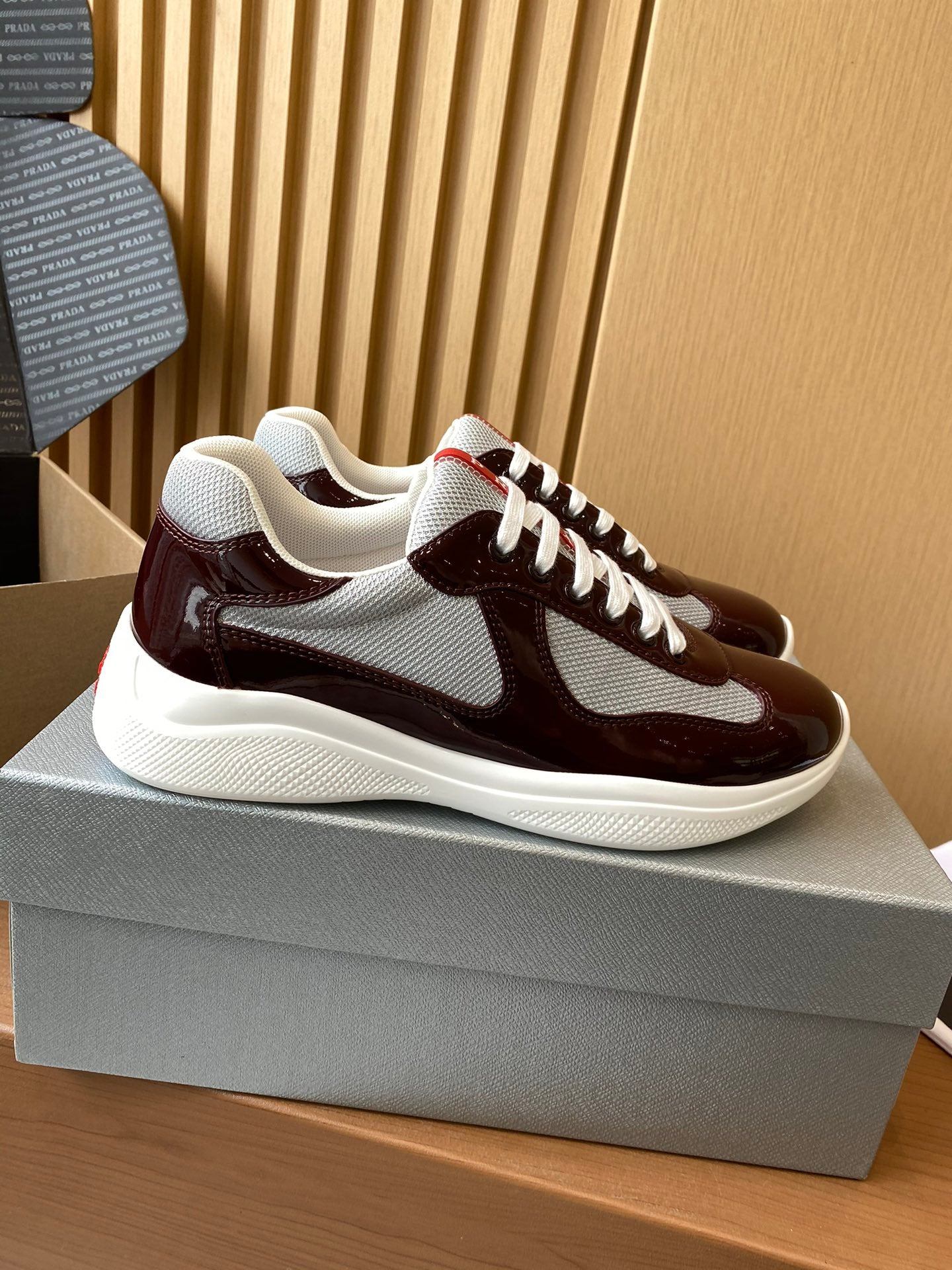 Burgundy and white low-top sneakers with white laces and side panels, red logo detail