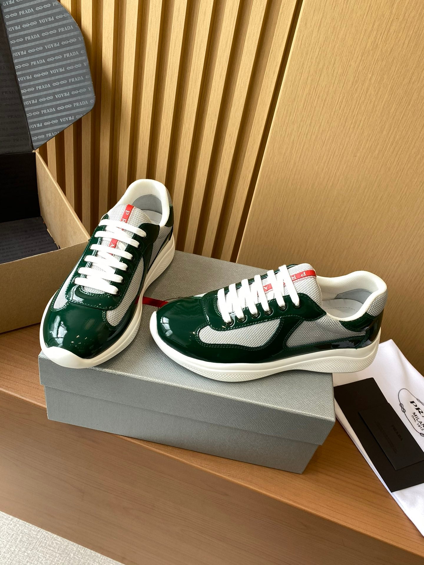 Prada unisex green sneakers on box, angled view, white rubber sole