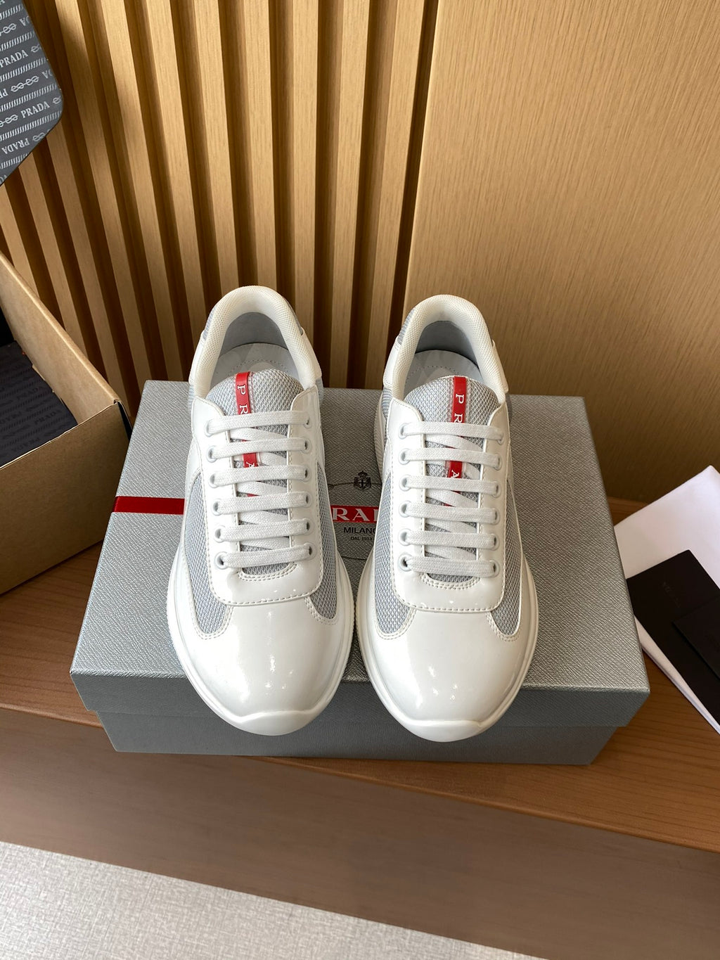 Prada unisex white sneakers, red accent lace eyelets, lace-up front view