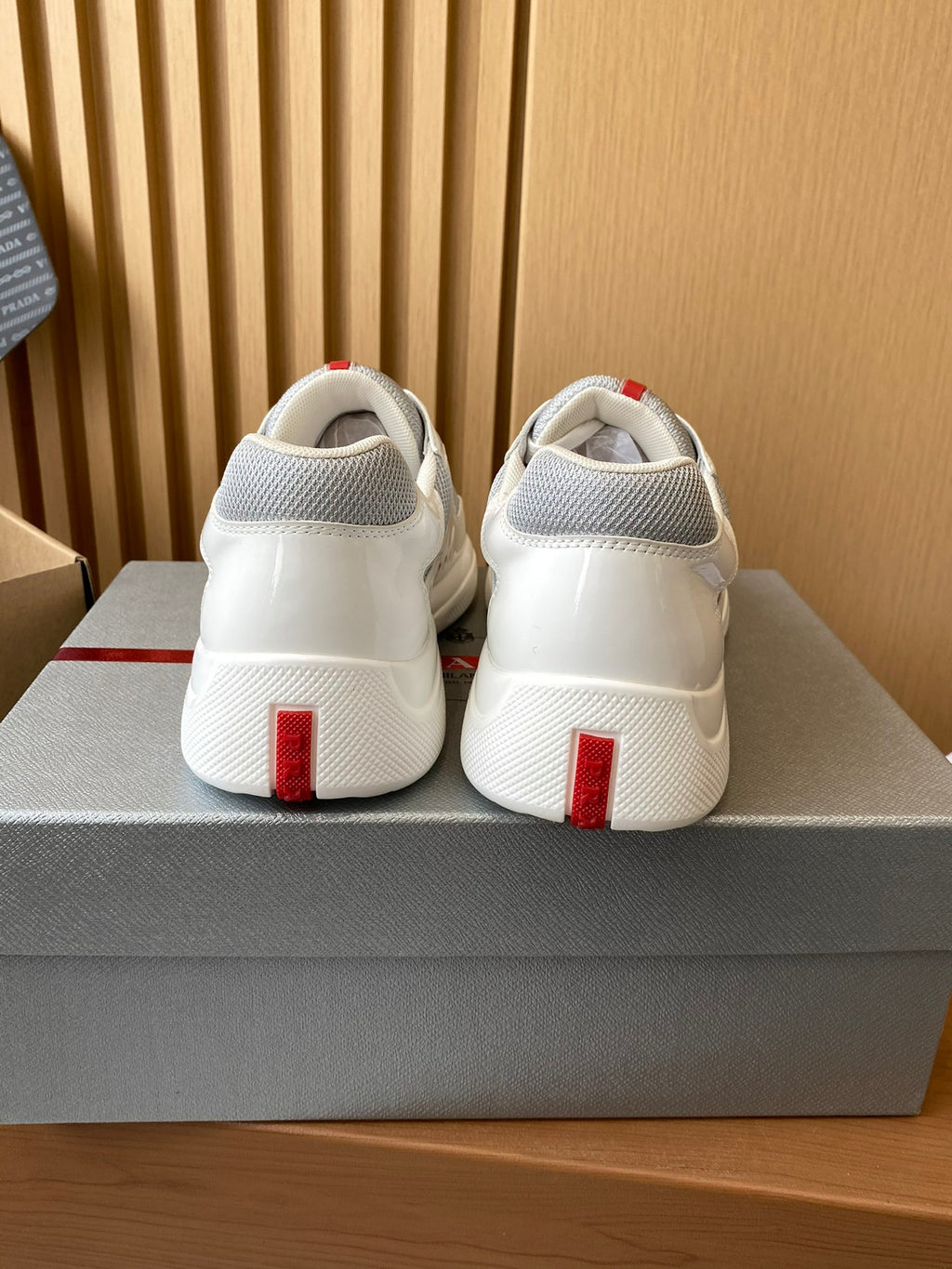 Prada unisex white sneakers, rear view with red vertical heel stripe