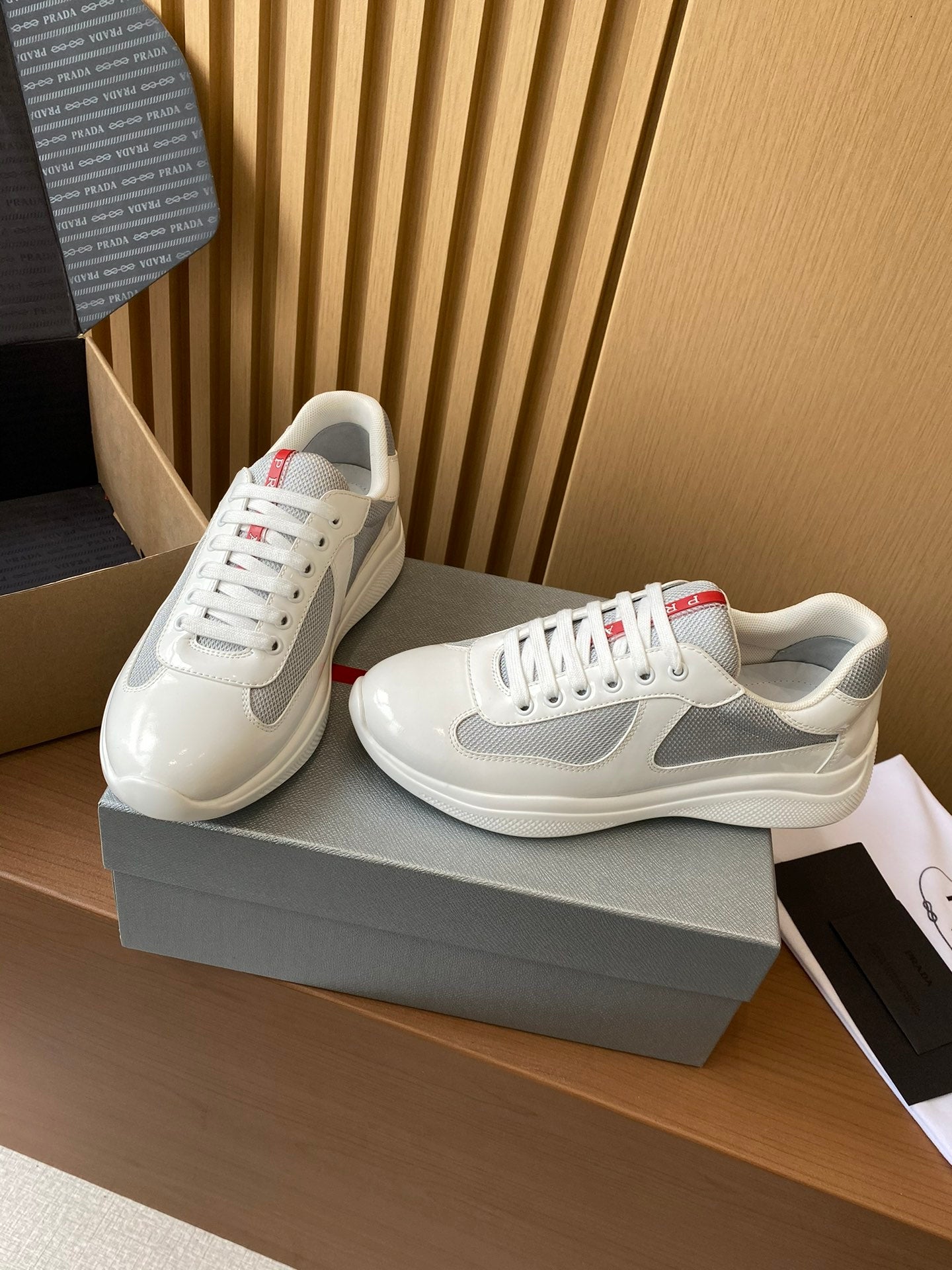 Prada unisex white and gray sneakers, lace-up with red tongue stripe, side view