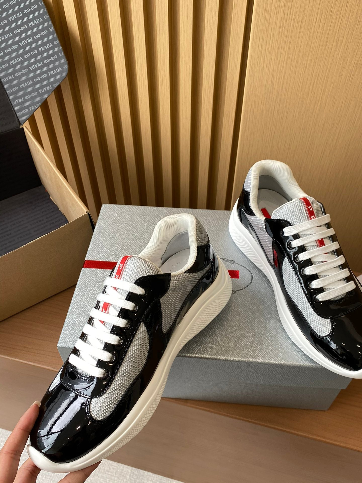 Prada unisex sneakers, black patent with grey swoosh, white laces, red heel label