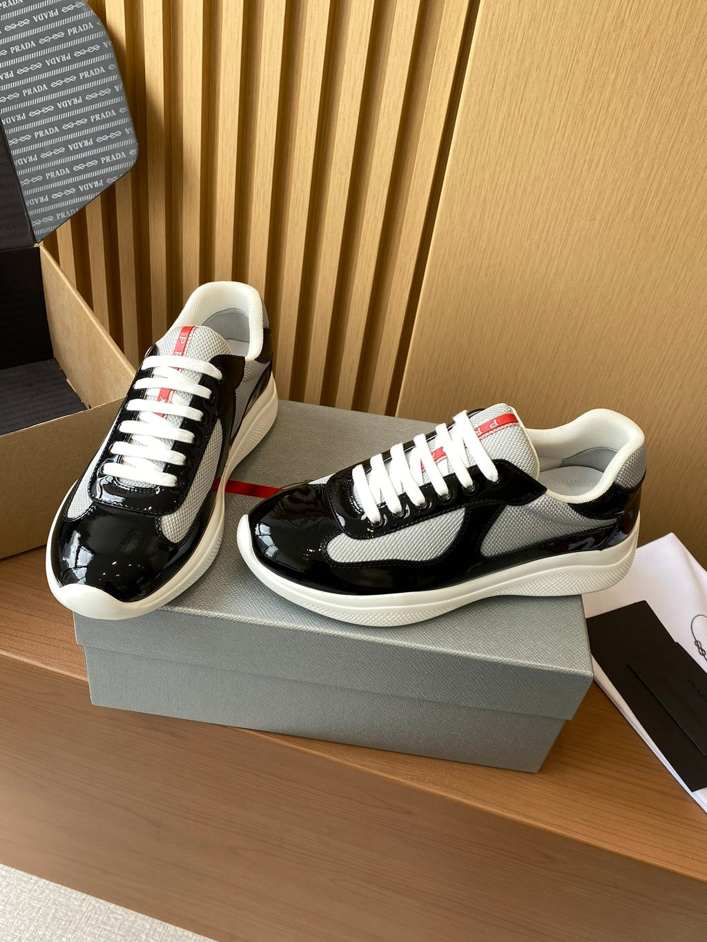 Prada unisex sneakers, black patent with grey swoosh, white laces and red heel tab