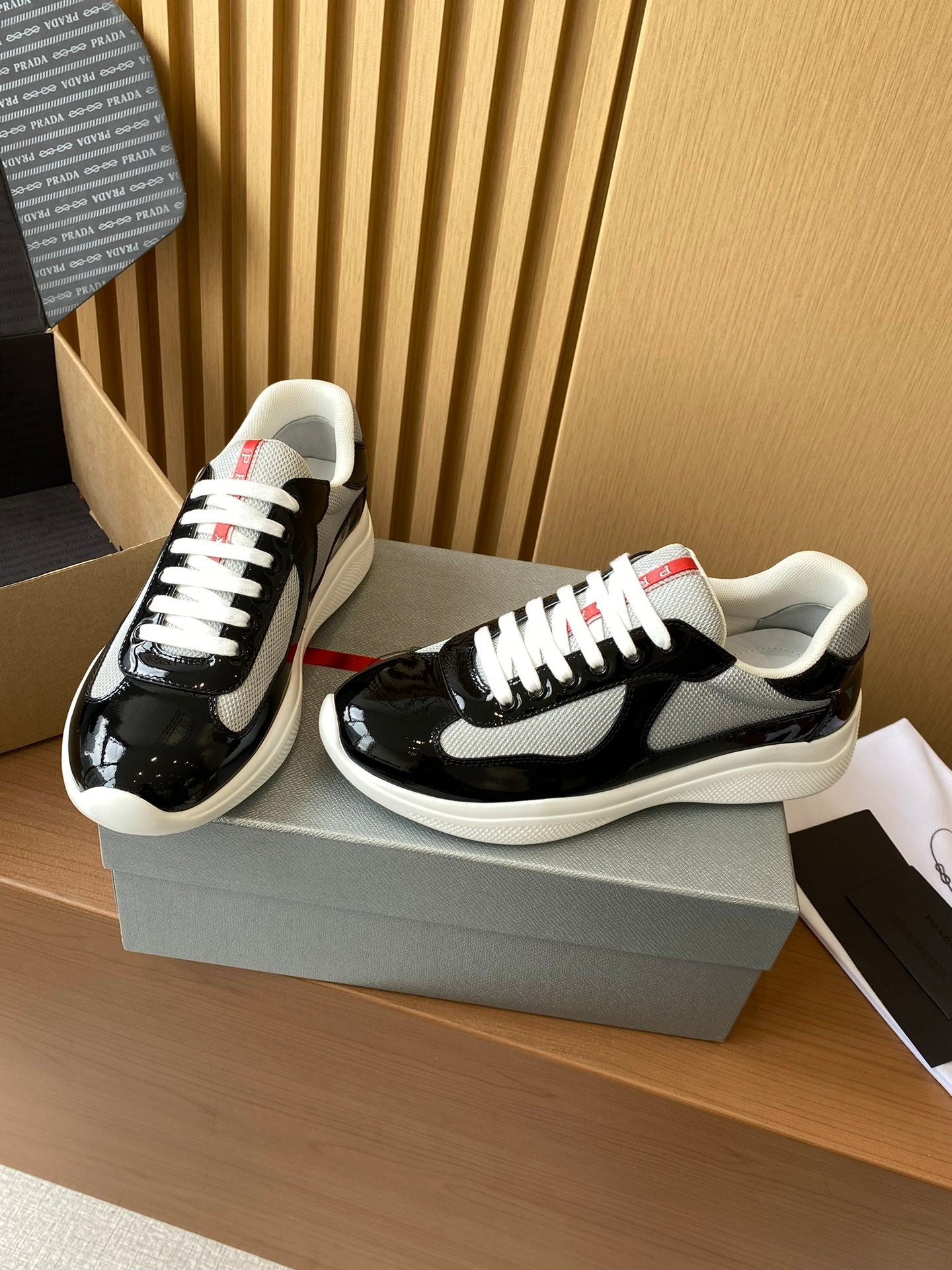 Prada unisex sneakers, black patent with grey swoosh, white laces and red heel tab