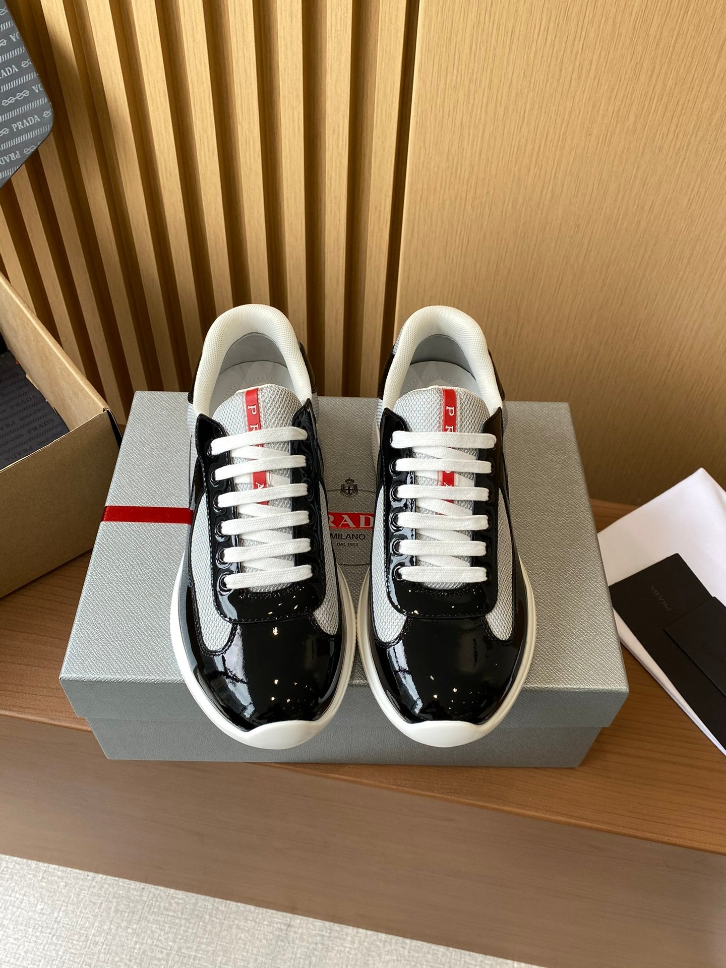 Prada unisex low-top sneakers, black patent with grey swoosh and white laces