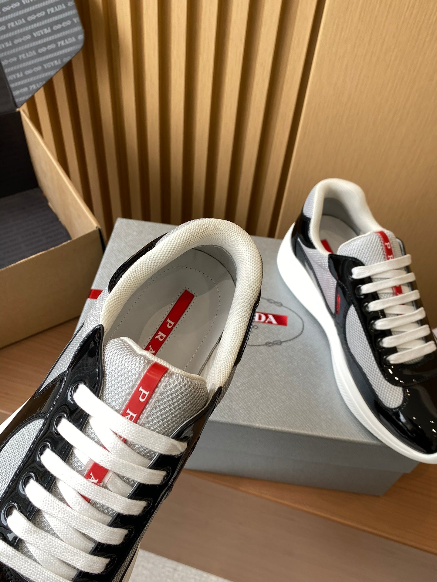 Prada unisex sneakers, black patent with white mesh lining and red tongue label