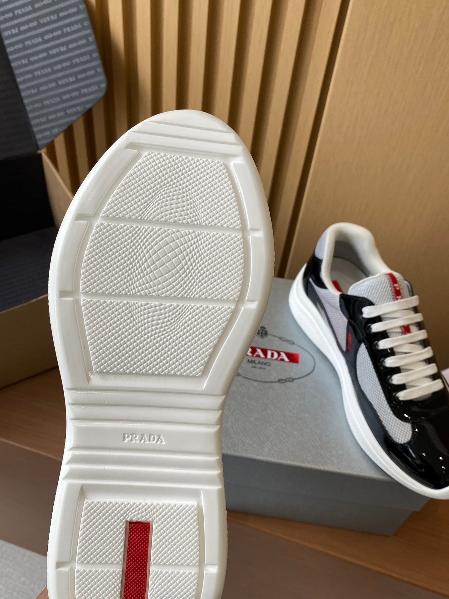 Prada unisex sneaker outsole, white tread with Prada print; black upper visible