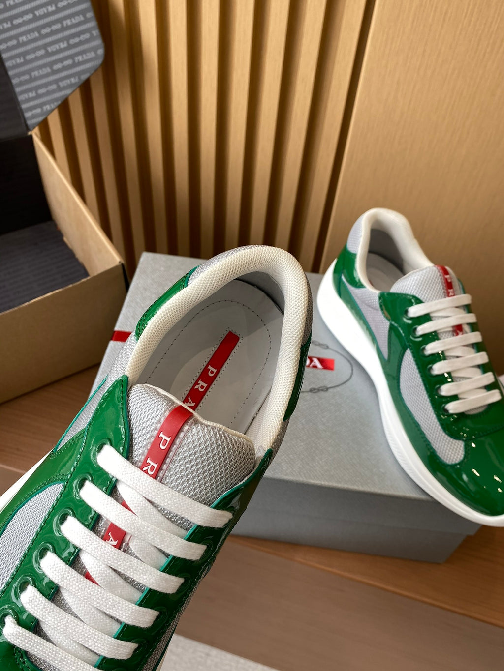 Prada unisex sneakers showing gray lining and red logo label at tongue