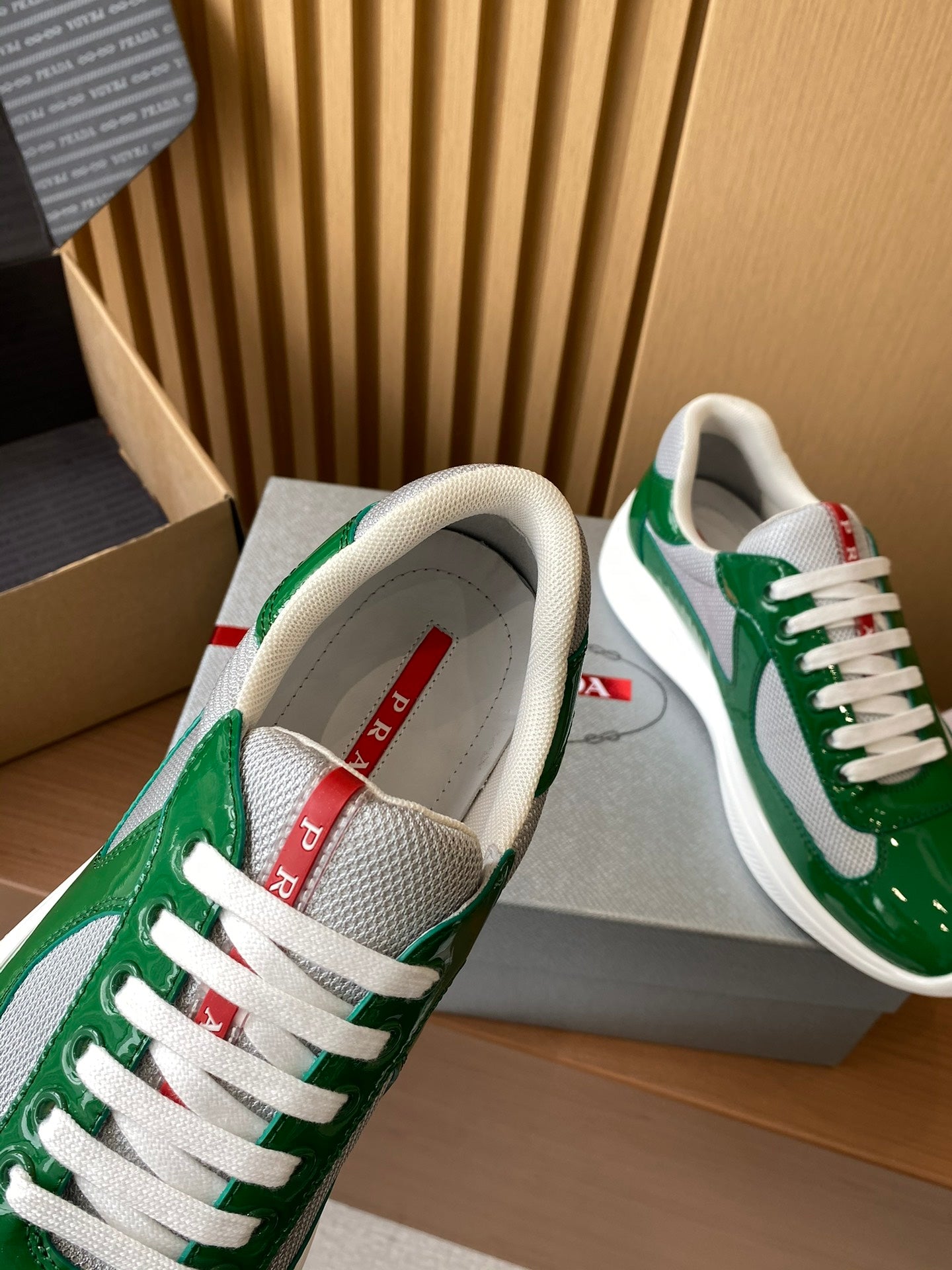 Prada unisex sneakers showing gray lining and red logo label at tongue