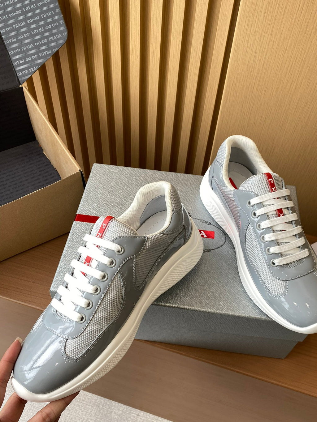 Light gray unisex sneakers with white laces and red logo heel tags, close side view