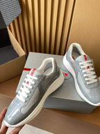 Light gray unisex sneakers with white laces and red logo heel tags, close side view