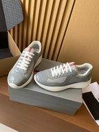 Light gray unisex sneakers with white laces and red heel/stripe accents, angled side view