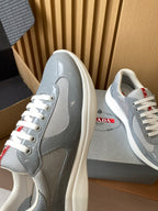 Light gray unisex sneakers shown from the side with white laces and red label detail