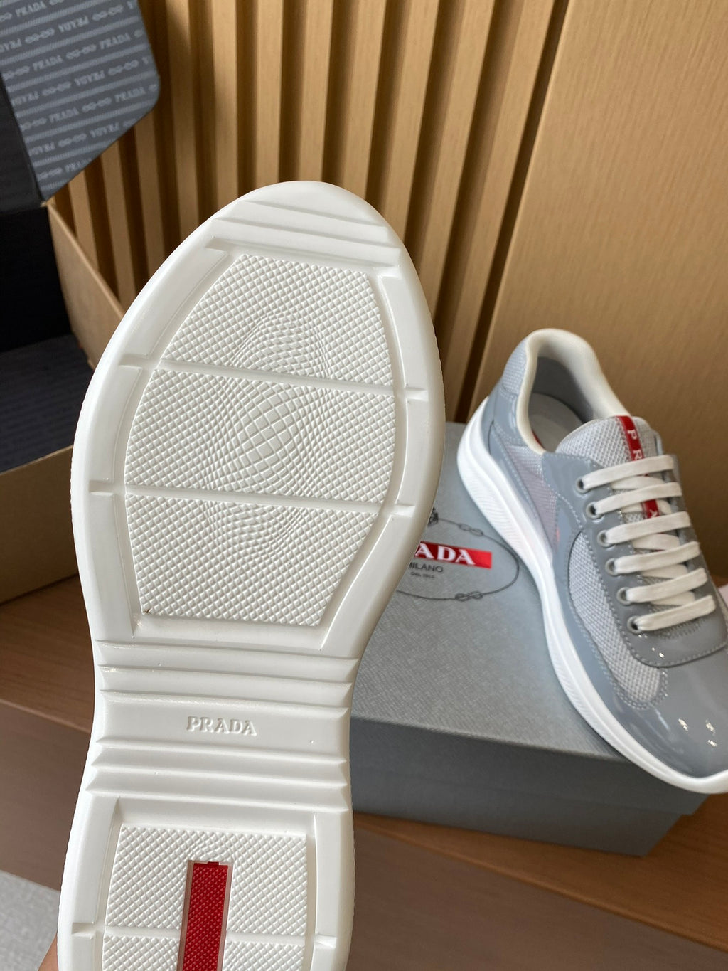 White outsole view of light gray unisex sneakers with red logo detail on the side