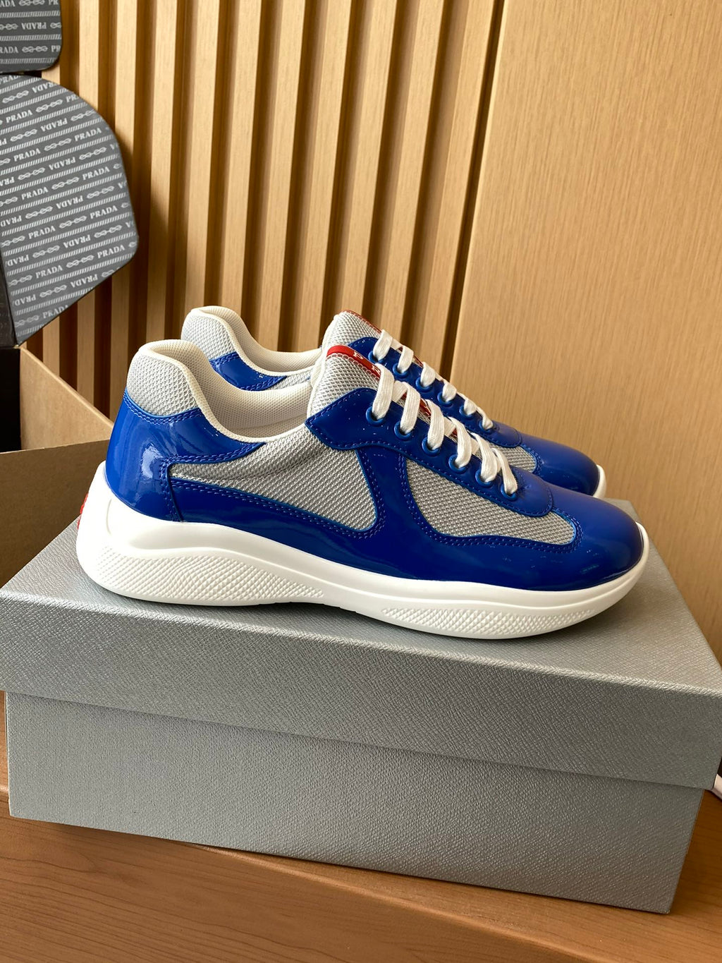Prada unisex sneakers side view, blue upper with gray swoosh and white laces
