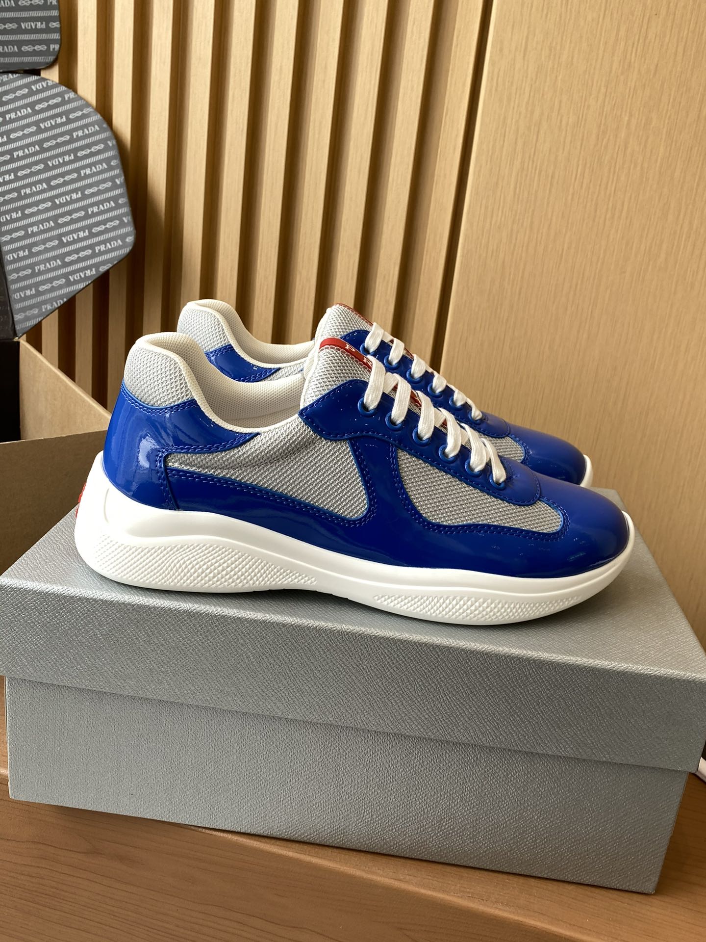 Prada unisex sneakers side view, blue upper with gray swoosh and white laces