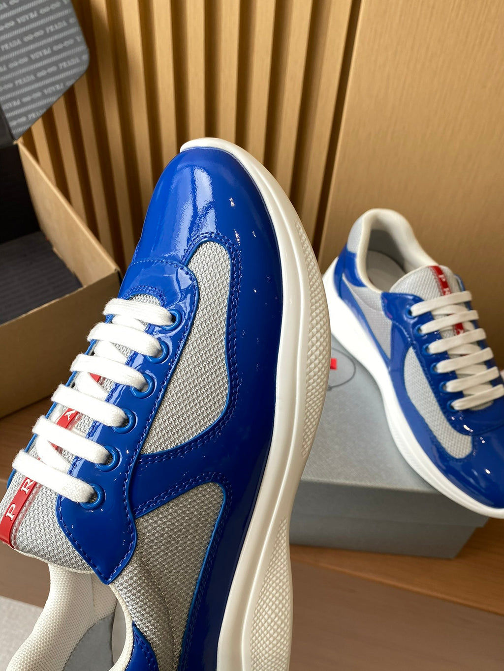 Prada unisex sneakers upper close-up, shiny blue leather with textured gray panel