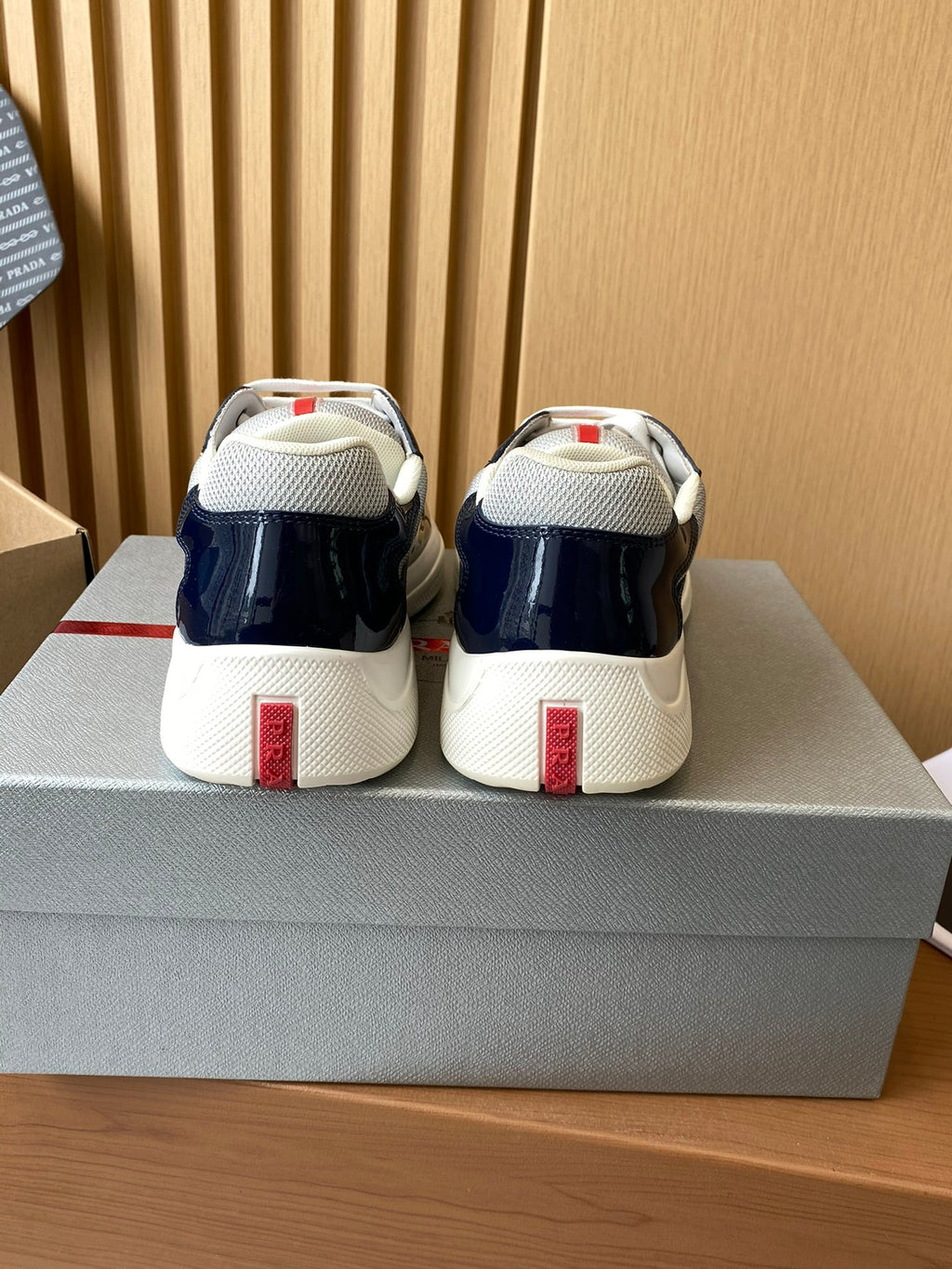 Prada low-top sneakers heel view in navy and white, with red logo patch