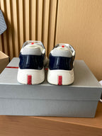 Prada low-top sneakers heel view in navy and white, with red logo patch