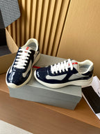 Prada navy and white low-top sneakers on a box, lace-up front and side view