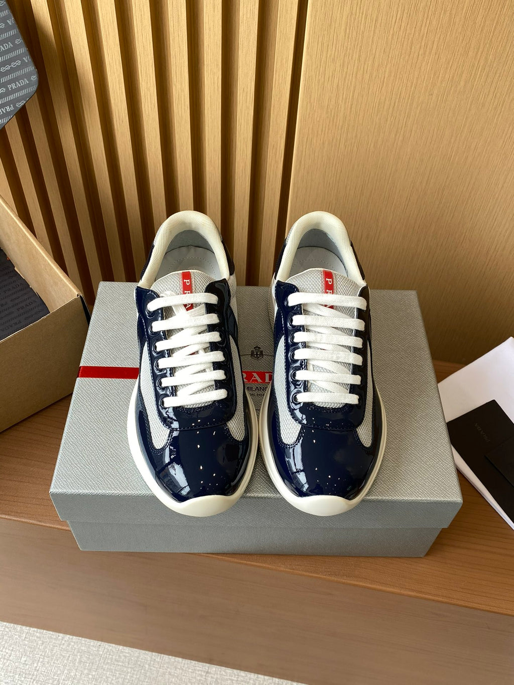 Prada low-top sneakers in dark navy and white, lace-up style, shown as a pair