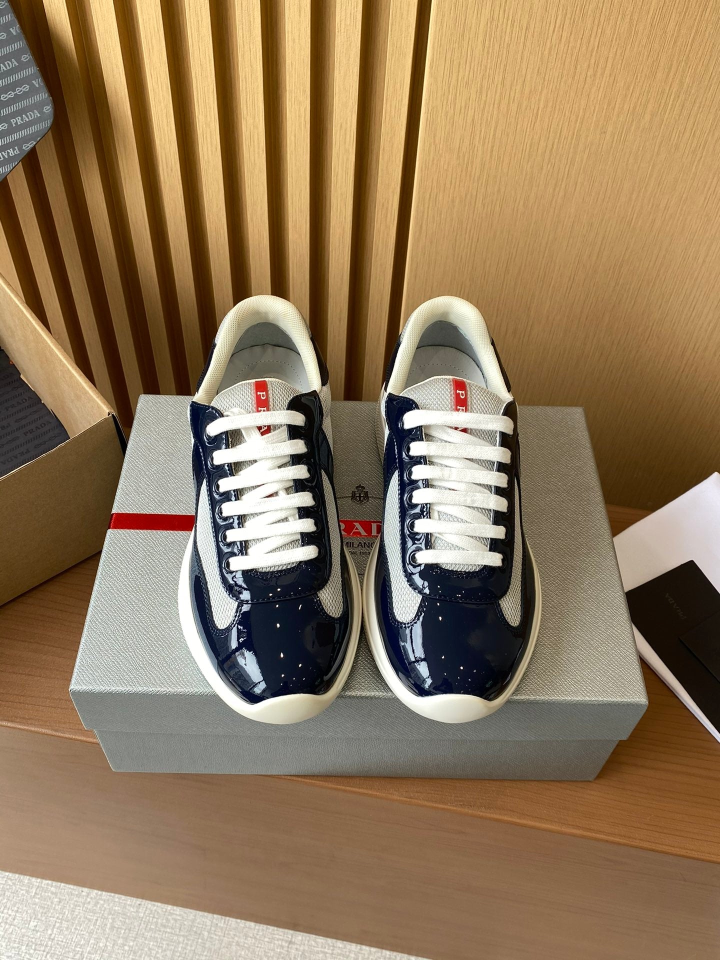Prada low-top sneakers in dark navy and white, lace-up style, shown as a pair