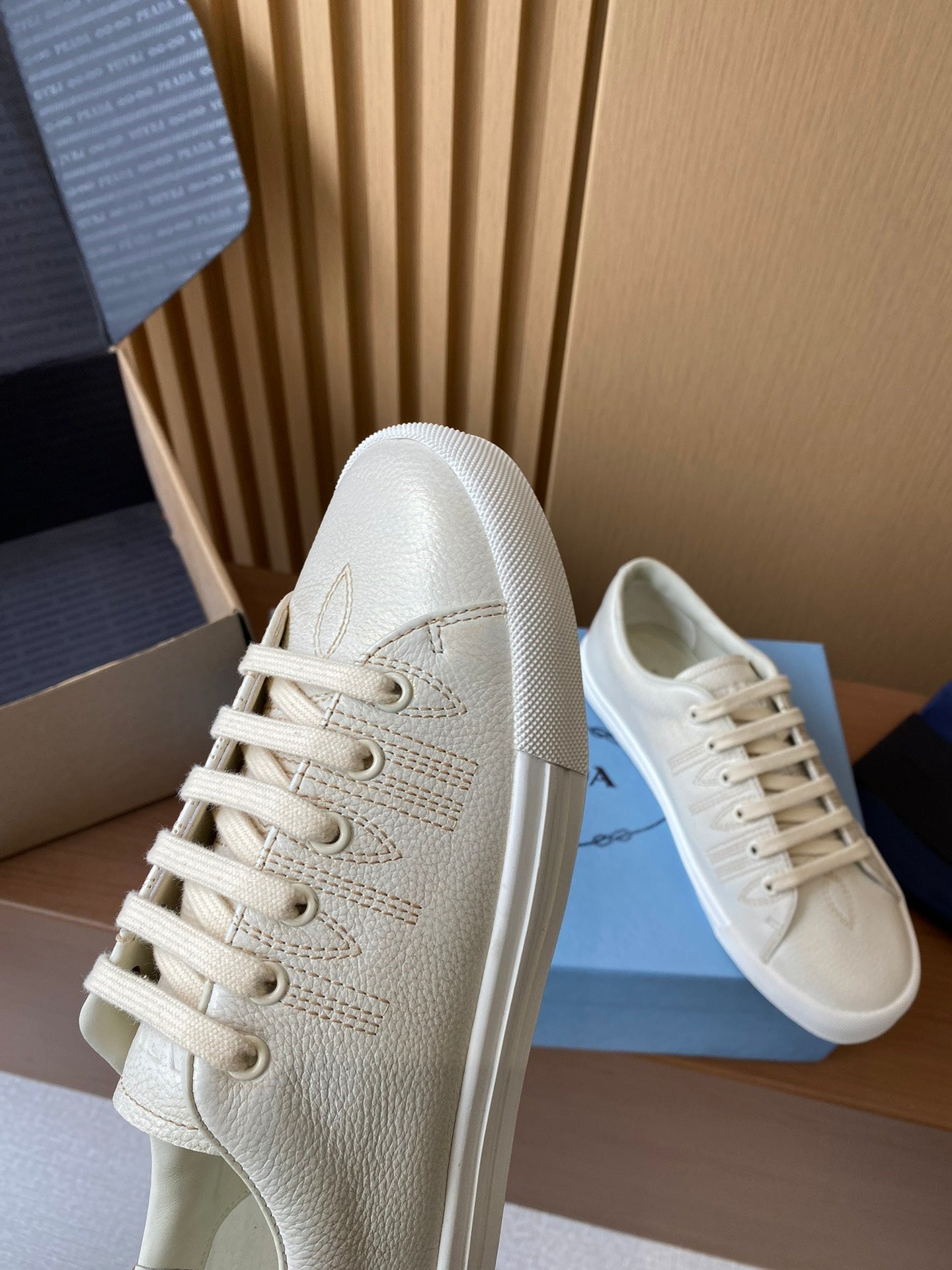 Prada unisex low-top sneakers, cream textured uppers with lace-up front and rounded toe.