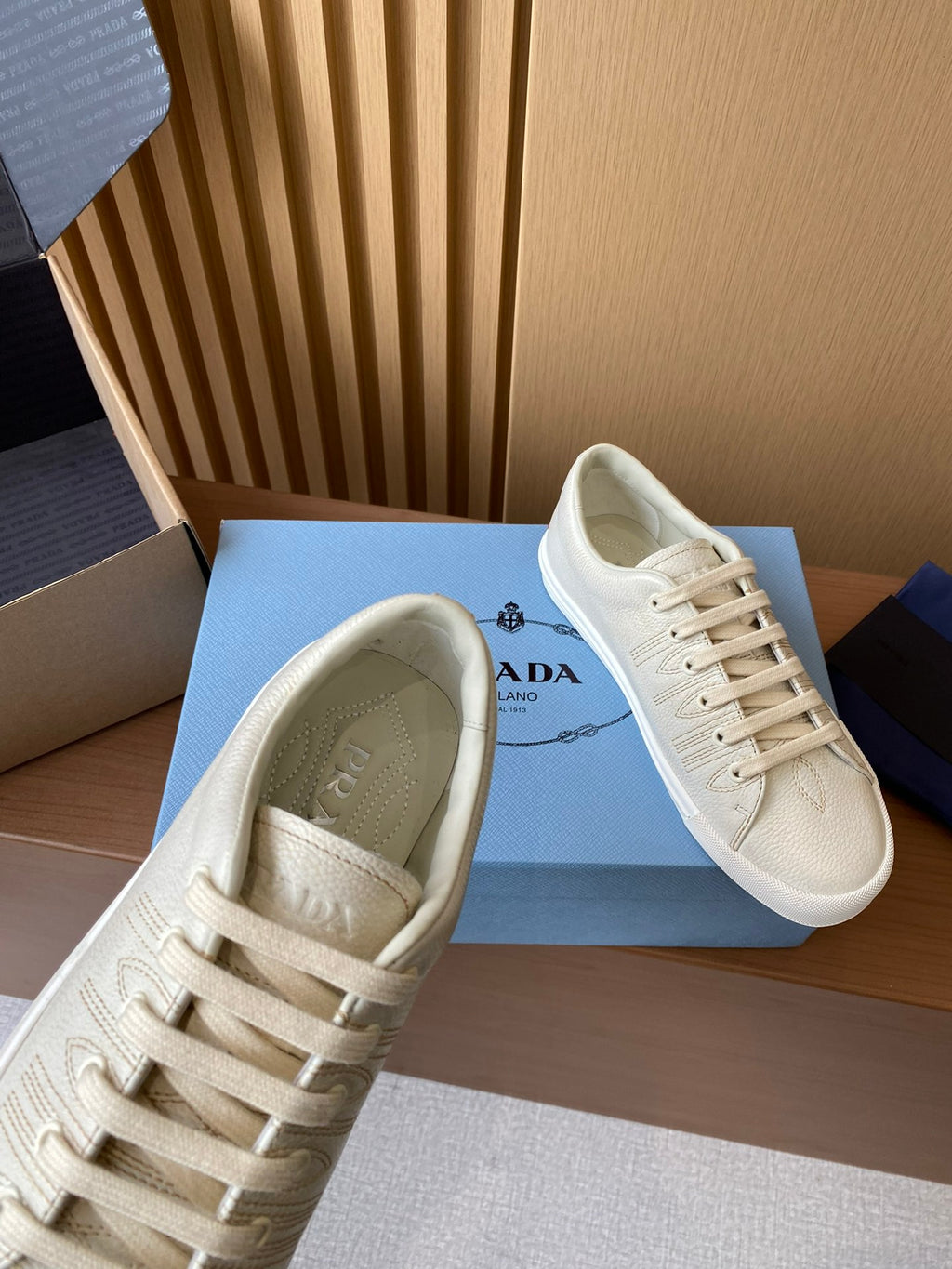 Prada unisex low-top sneakers, cream uppers with lace-up front and padded interior lining.