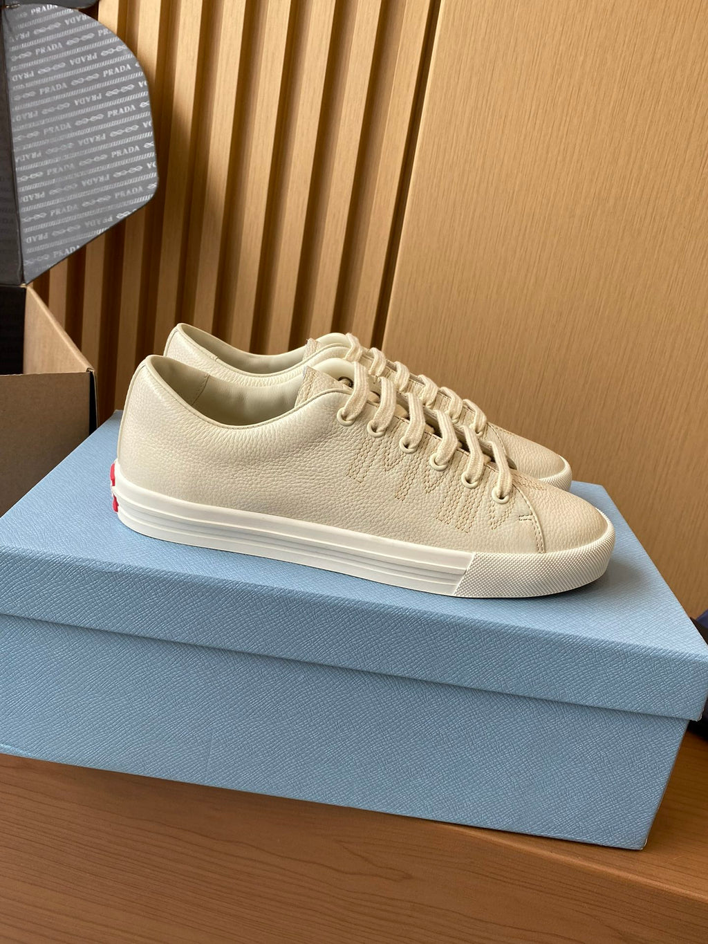 Prada unisex low-top sneakers, cream uppers with lace-up front and white rubber sole.