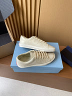 Prada unisex low-top sneakers, cream uppers with lace-up front and white rubber sole.