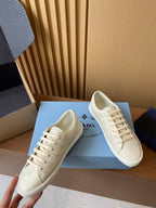 Prada unisex low-top sneakers, cream uppers with lace-up front and cushioned collar.