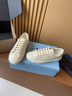 Prada unisex low-top sneakers, cream uppers with lace-up front and stitched side panels.