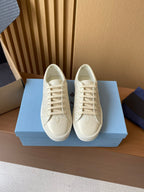 Prada unisex low-top sneakers, cream uppers with lace-up front and smooth toe cap.