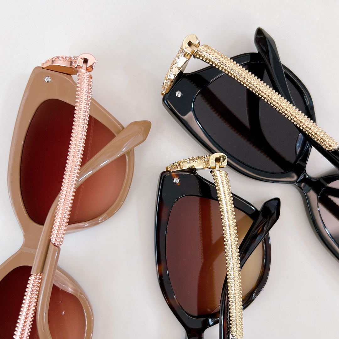 Bvlgari sunglasses pair with pink and black frames, gold chain temples, tinted lenses