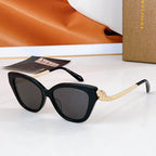 Bvlgari cat-eye sunglasses with dark frames, gold chain temple details, dark lenses