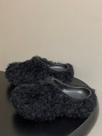 Black fuzzy slide sandals with rounded toe and visible gray footbeds