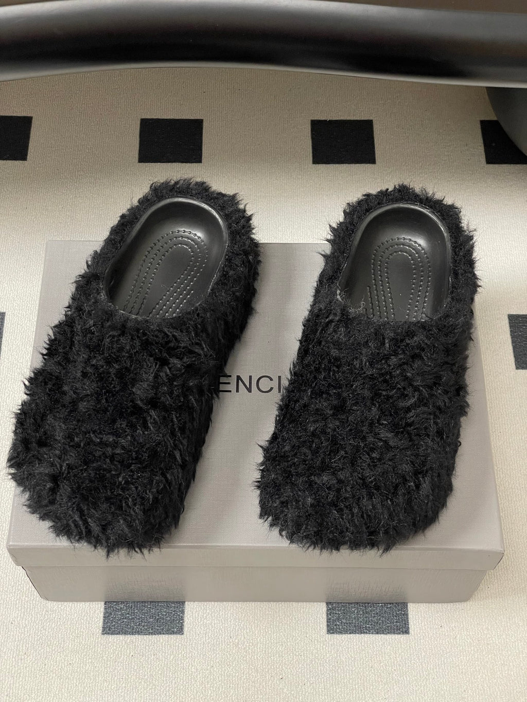 Black fuzzy slide sandals showing BALENCIAGA text on insoles