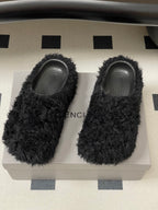 Black fuzzy slide sandals showing BALENCIAGA text on insoles