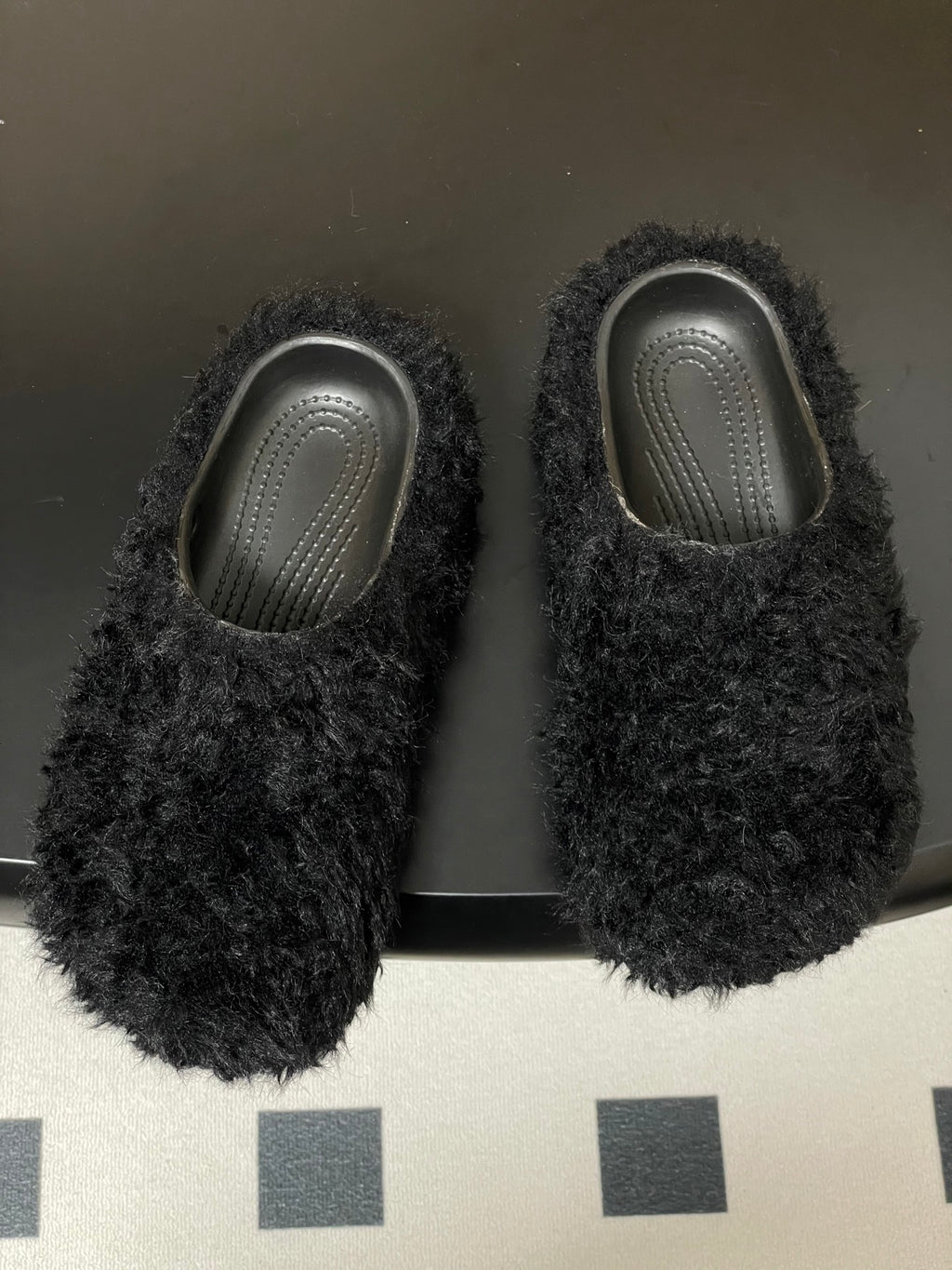 Pair of black shaggy slide sandals with textured gray insoles