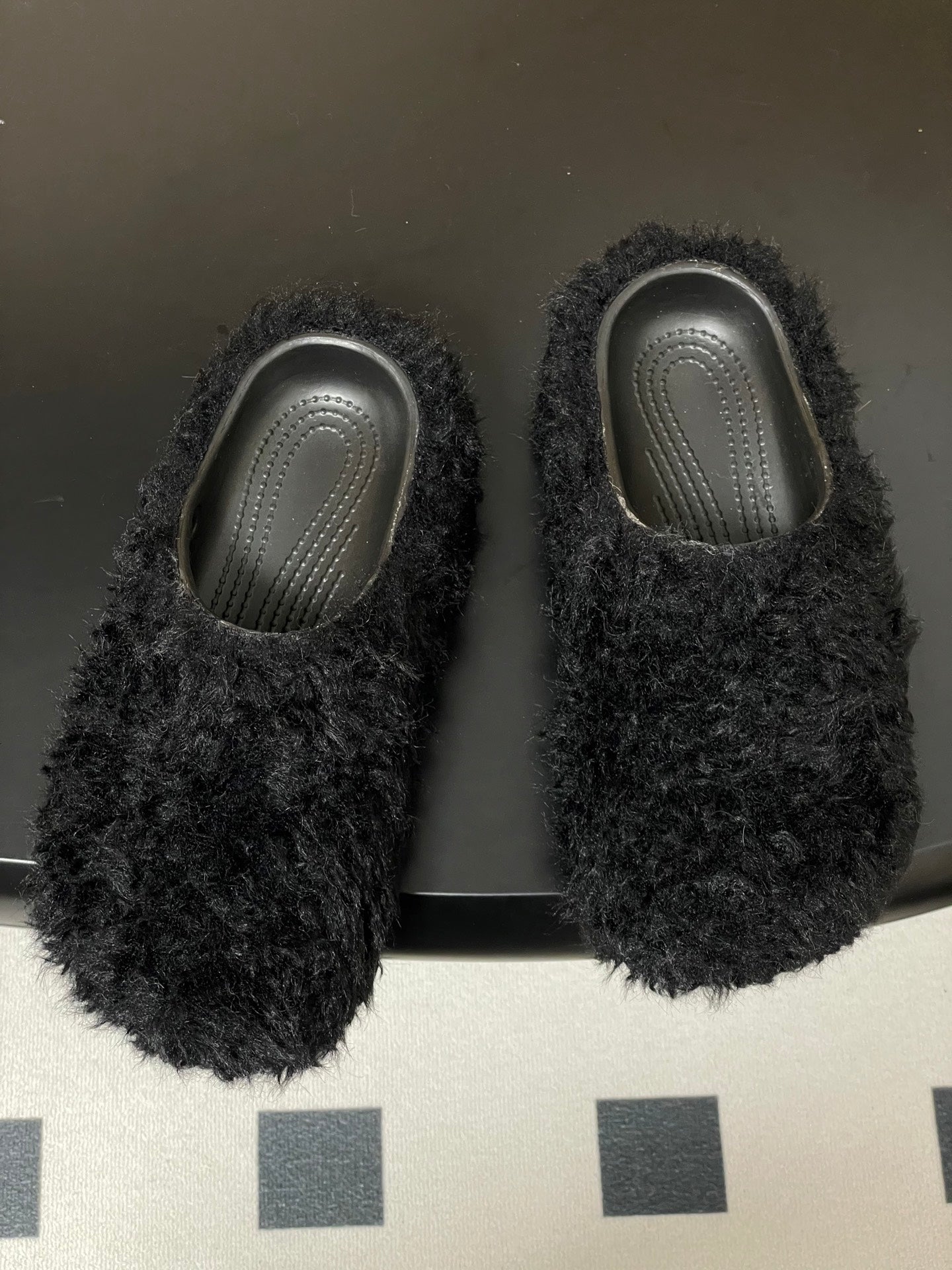 Pair of black shaggy slide sandals with textured gray insoles