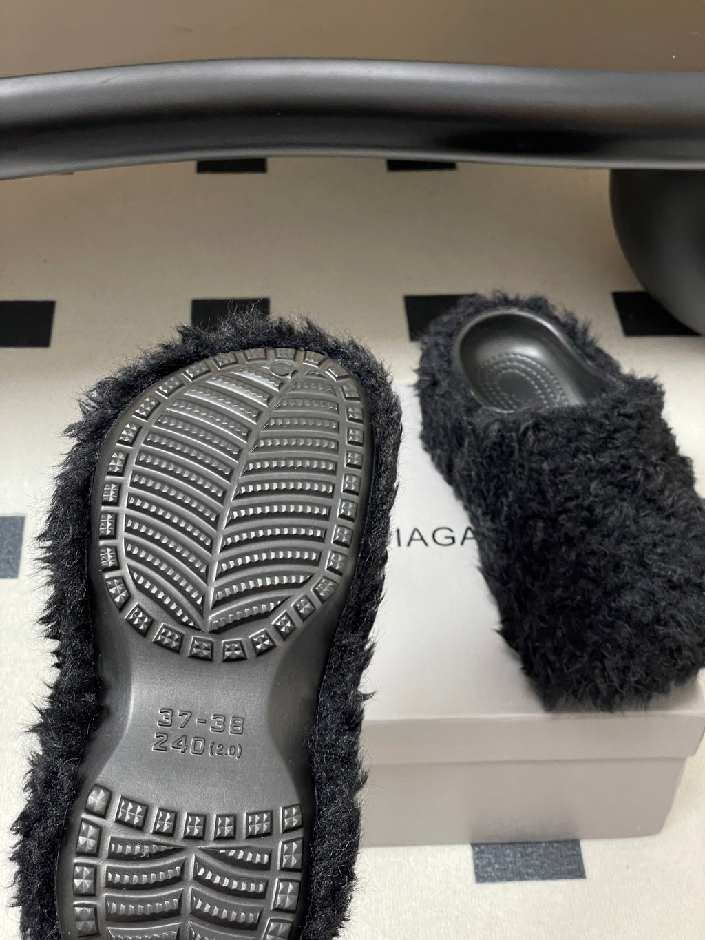 Black fuzzy slide sandals showing treaded outsoles with studs