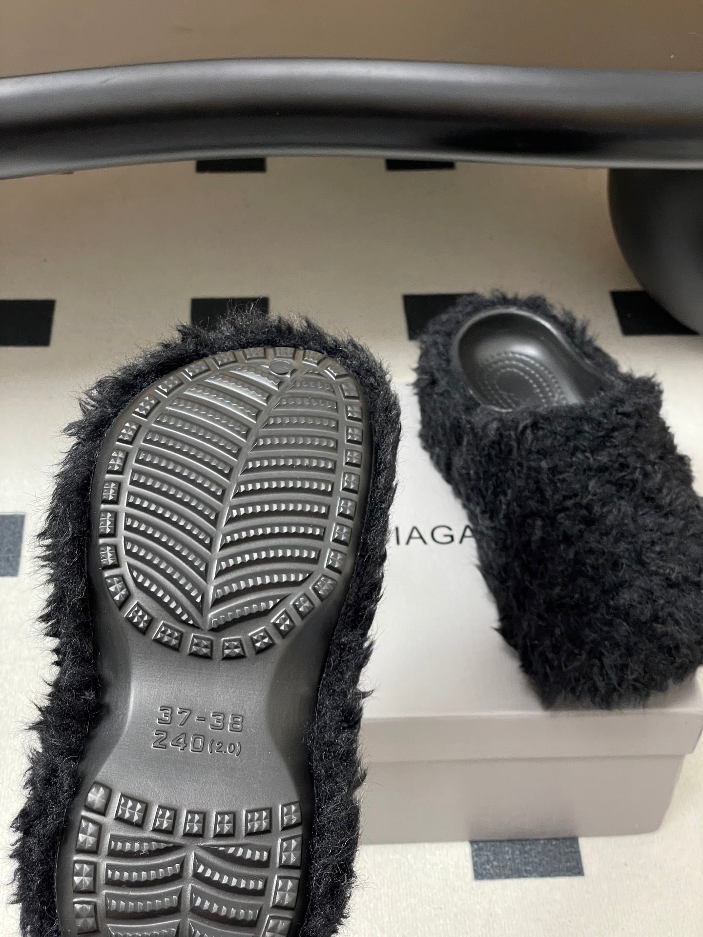 Black fuzzy slide sandals showing treaded outsoles with studs