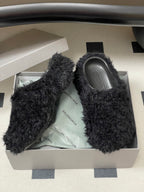 Black shaggy slide sandals with gray footbeds inside white shoebox