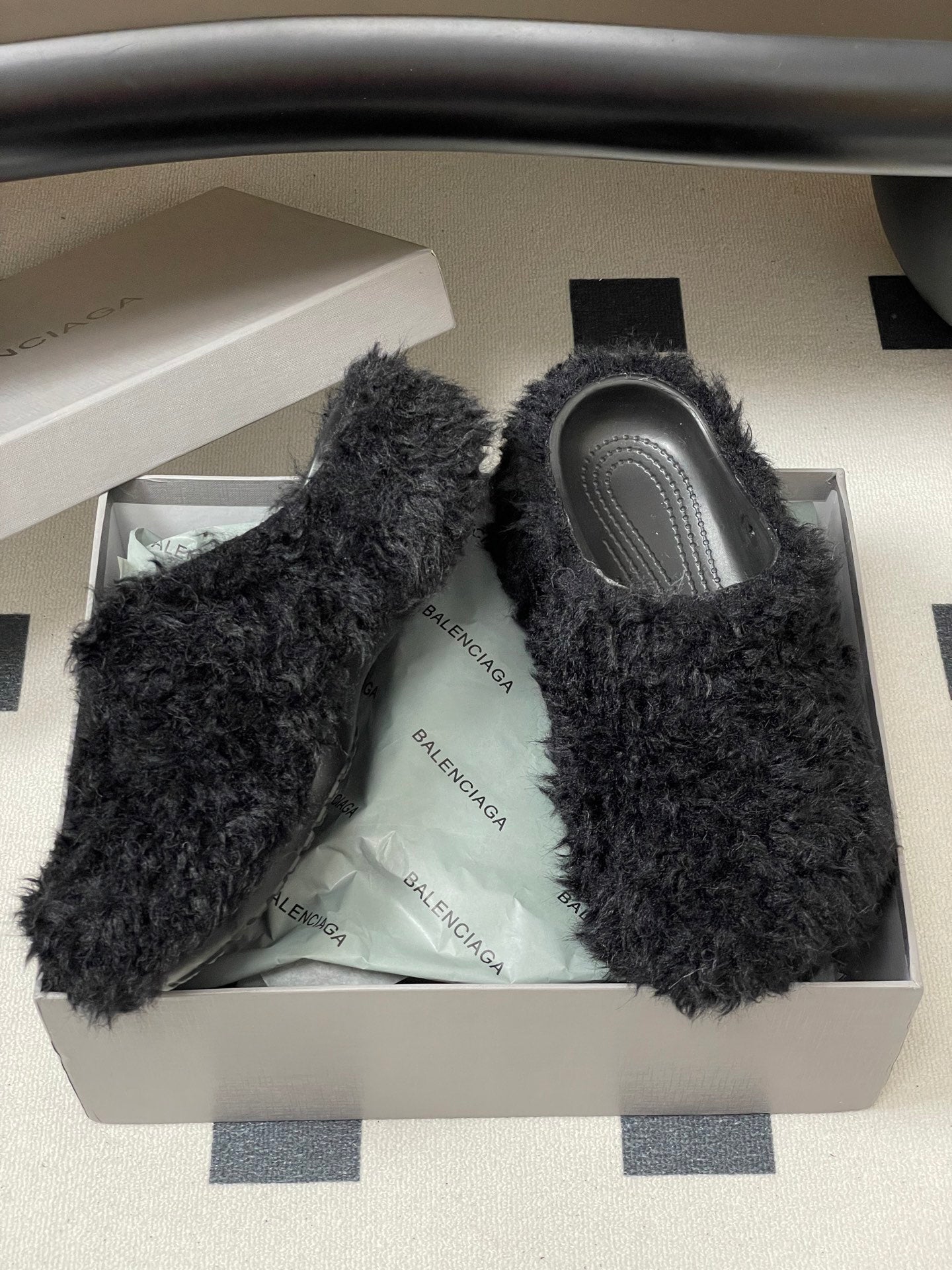 Black shaggy slide sandals with gray footbeds inside white shoebox