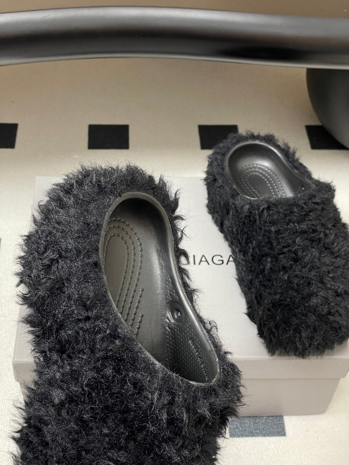 Black fuzzy slide sandals with oval opening and gray patterned insoles