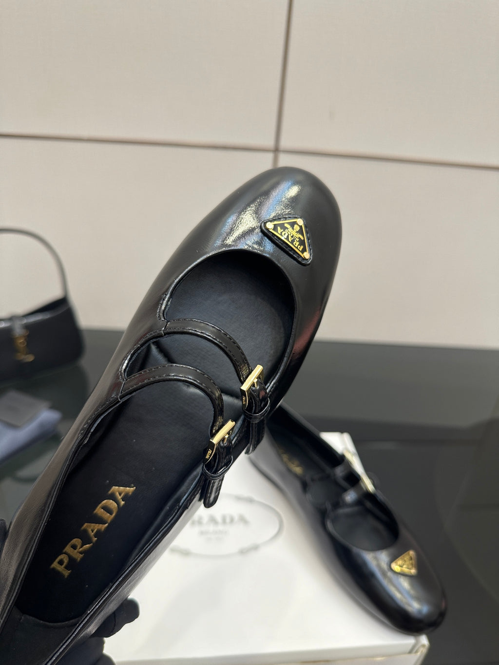 Prada women's black leather loafer close-up with gold-tone logo plate and buckle