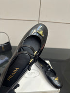 Prada women's black leather loafer close-up with gold-tone logo plate and buckle